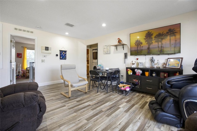 living room featuring light wood-type flooring and a textured ceiling