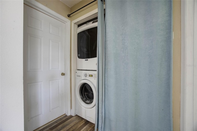 laundry area with stacked washing maching and dryer and dark hardwood / wood-style floors