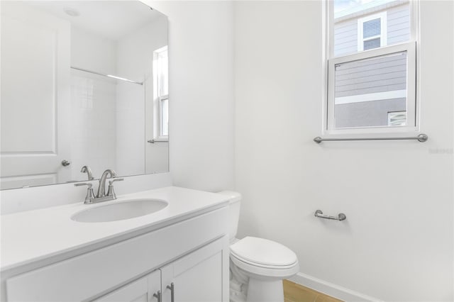 bathroom with walk in shower, vanity, and toilet