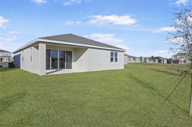 back of house with central AC unit and a yard