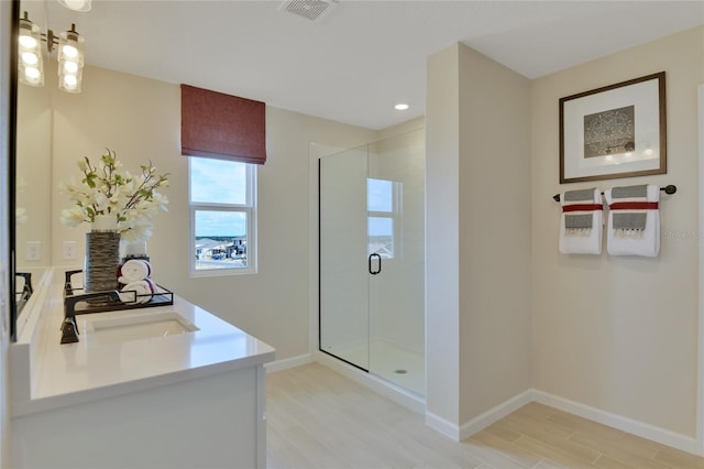 bathroom with an enclosed shower, vanity, and wood-type flooring