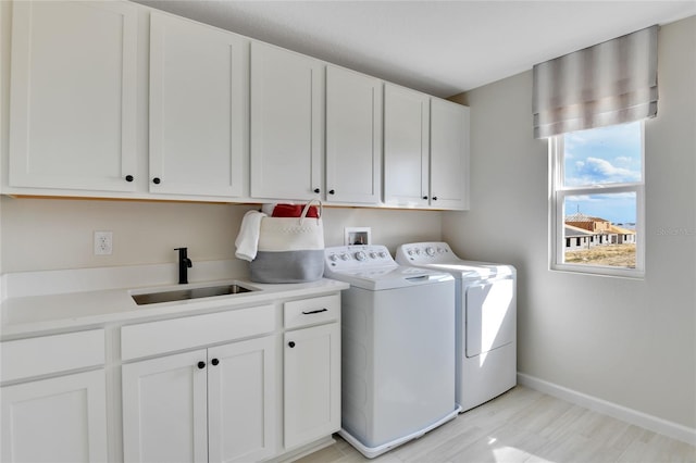 washroom with cabinets, sink, washing machine and clothes dryer, and light hardwood / wood-style flooring