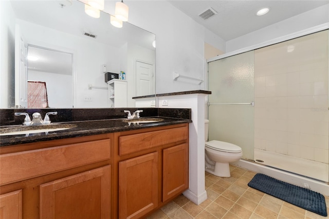 bathroom featuring a shower with shower door, tile patterned flooring, toilet, and dual bowl vanity