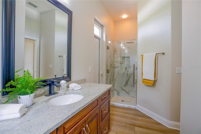 bathroom with hardwood / wood-style flooring, vanity, and a shower with shower door