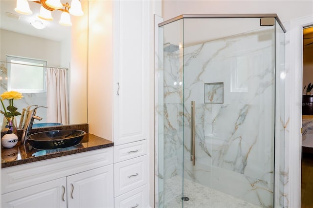 bathroom featuring a tile shower, vanity, and an inviting chandelier