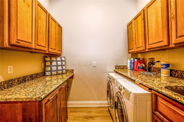 kitchen featuring washing machine and clothes dryer, light stone countertops, and light wood-type flooring