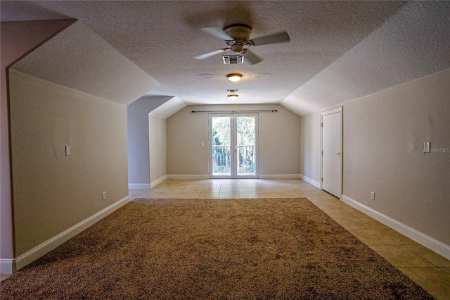 bonus room featuring vaulted ceiling, light tile patterned floors, ceiling fan, and a textured ceiling