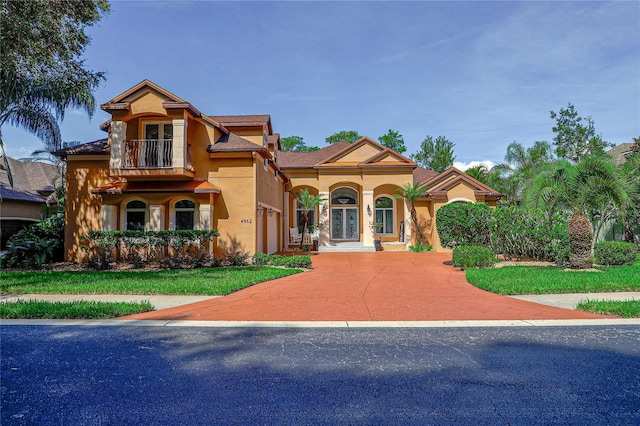 mediterranean / spanish-style house featuring a front yard and a balcony