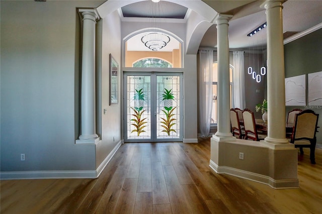 foyer featuring decorative columns, crown molding, dark hardwood / wood-style flooring, and french doors