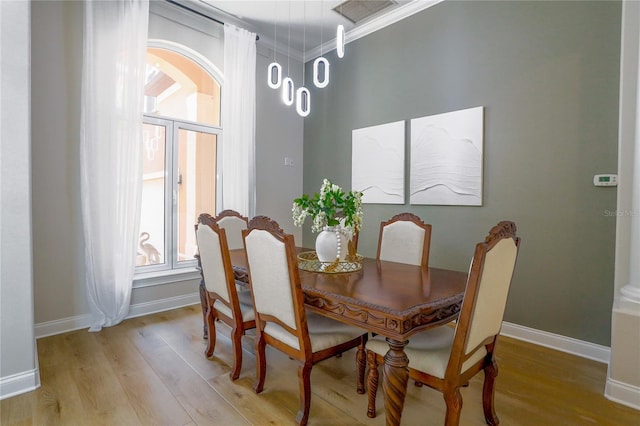 dining room with crown molding and light hardwood / wood-style flooring