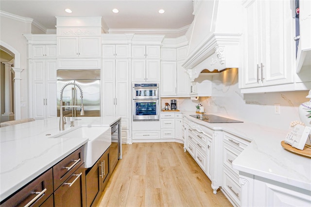 kitchen featuring sink, crown molding, stainless steel appliances, light stone countertops, and white cabinets