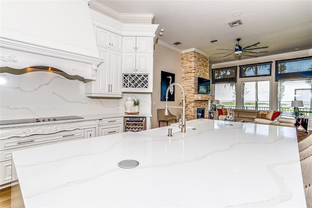 kitchen with light stone counters, wine cooler, a fireplace, and crown molding