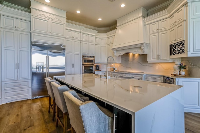 kitchen featuring stainless steel appliances, dark hardwood / wood-style flooring, a kitchen island with sink, and custom range hood