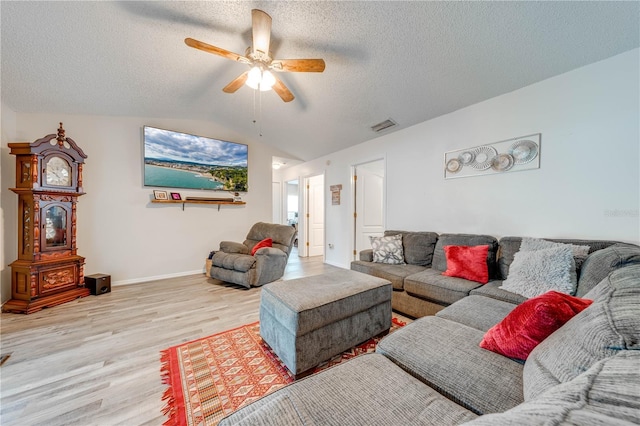 living room with ceiling fan, lofted ceiling, light hardwood / wood-style flooring, and a textured ceiling