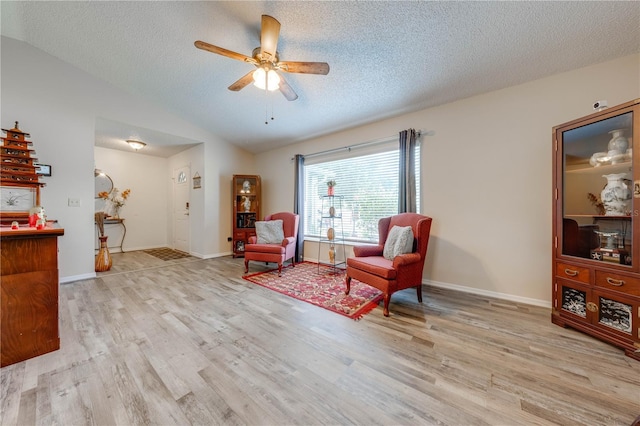 living area featuring ceiling fan, a textured ceiling, light hardwood / wood-style flooring, and lofted ceiling