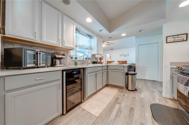 kitchen featuring light wood-type flooring, beverage cooler, ceiling fan, decorative backsplash, and vaulted ceiling