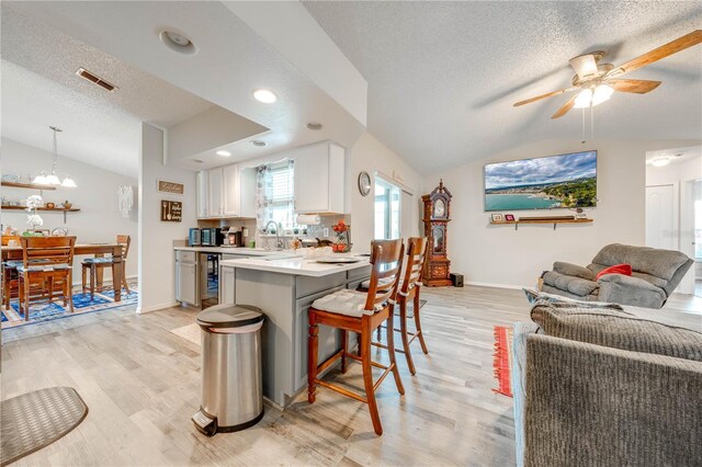 kitchen with lofted ceiling, a kitchen breakfast bar, and light wood-type flooring