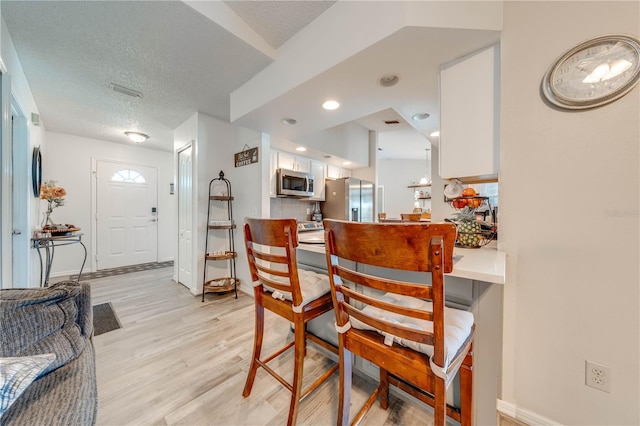 dining area featuring light hardwood / wood-style floors and a textured ceiling