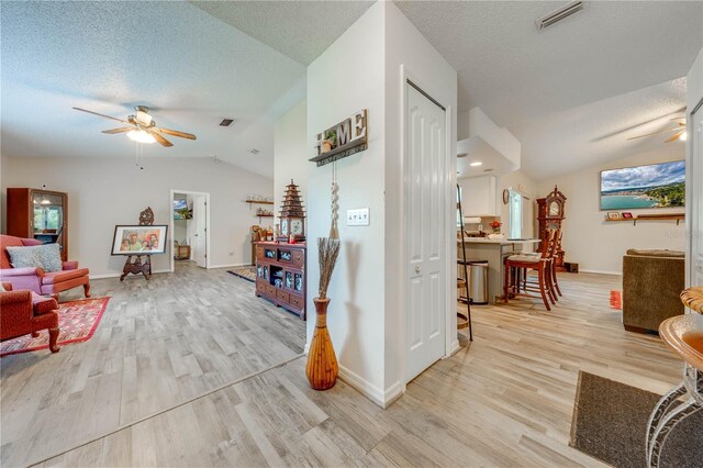 sitting room with a textured ceiling, lofted ceiling, ceiling fan, and light wood-type flooring