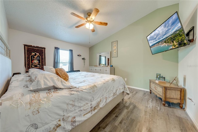 bedroom featuring lofted ceiling, light hardwood / wood-style floors, a textured ceiling, and ceiling fan