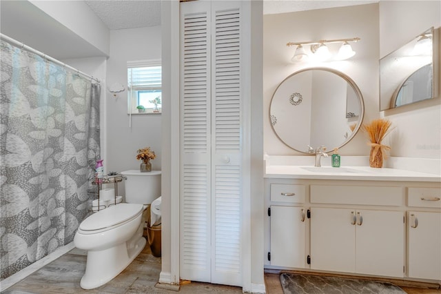 bathroom with hardwood / wood-style flooring, vanity, a textured ceiling, and toilet