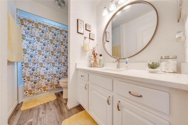 full bathroom featuring shower / bathtub combination with curtain, vanity, toilet, and hardwood / wood-style floors