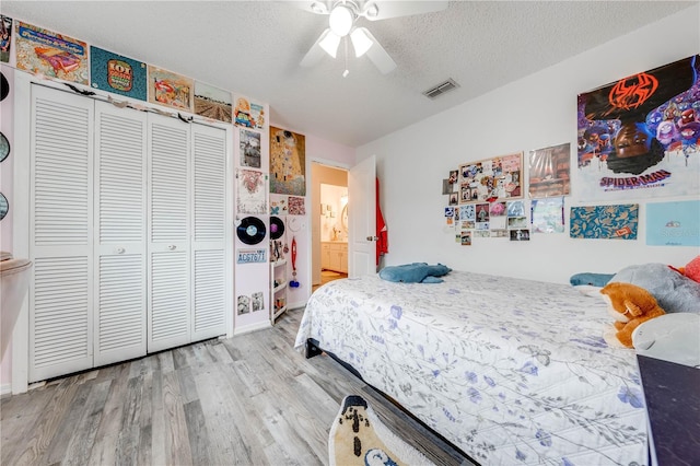 bedroom with hardwood / wood-style floors, a closet, a textured ceiling, and ceiling fan