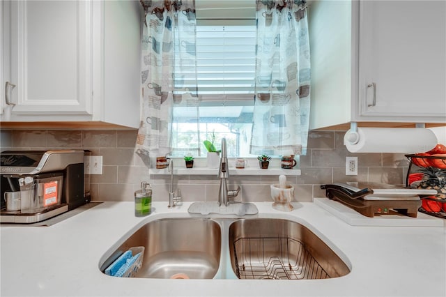 interior details featuring sink, backsplash, and white cabinets