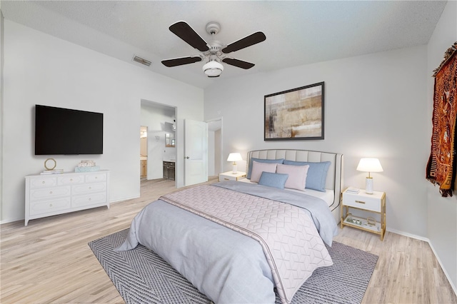 bedroom featuring ceiling fan, a textured ceiling, light hardwood / wood-style floors, and ensuite bath