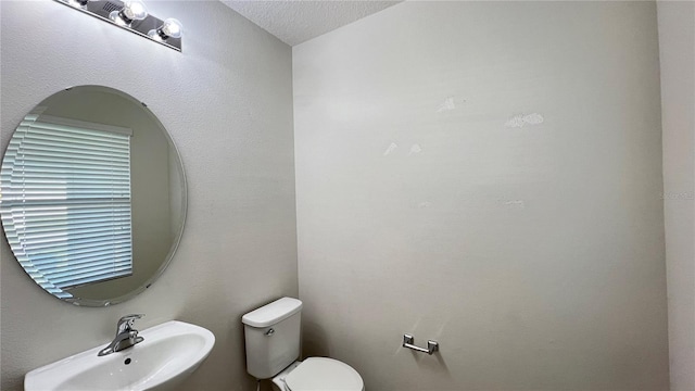 bathroom with a textured ceiling, sink, and toilet