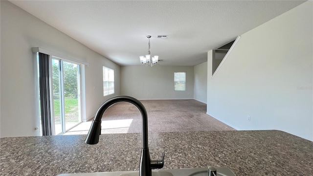 room details with carpet, a textured ceiling, hanging light fixtures, sink, and a chandelier