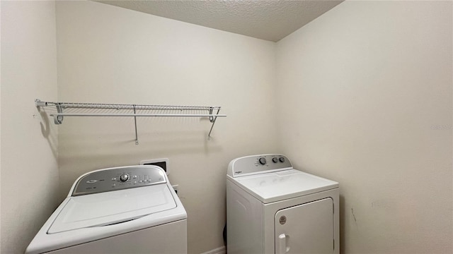 laundry area with separate washer and dryer and a textured ceiling