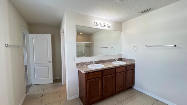 bathroom featuring vanity, a textured ceiling, tile patterned floors, and a shower with shower door