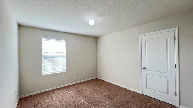 carpeted empty room featuring a textured ceiling