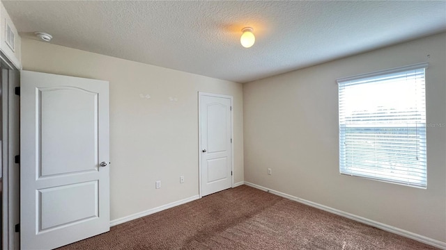 unfurnished bedroom with a textured ceiling and carpet