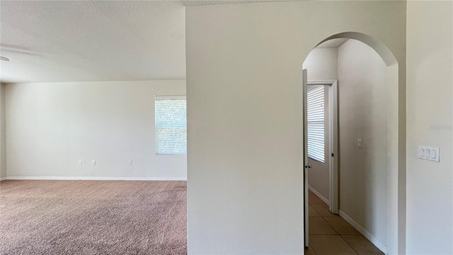 empty room with a textured ceiling and light carpet