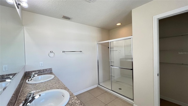 bathroom featuring walk in shower, vanity, a textured ceiling, and tile patterned floors