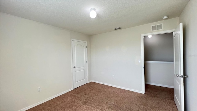 unfurnished bedroom with a textured ceiling and dark colored carpet