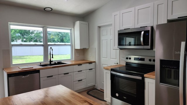 kitchen featuring wood counters, stainless steel appliances, white cabinetry, and sink