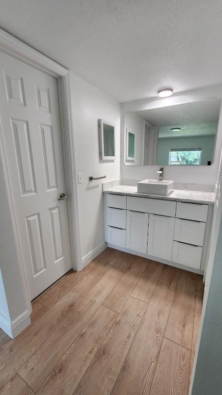 bathroom with hardwood / wood-style flooring, vanity, and a textured ceiling