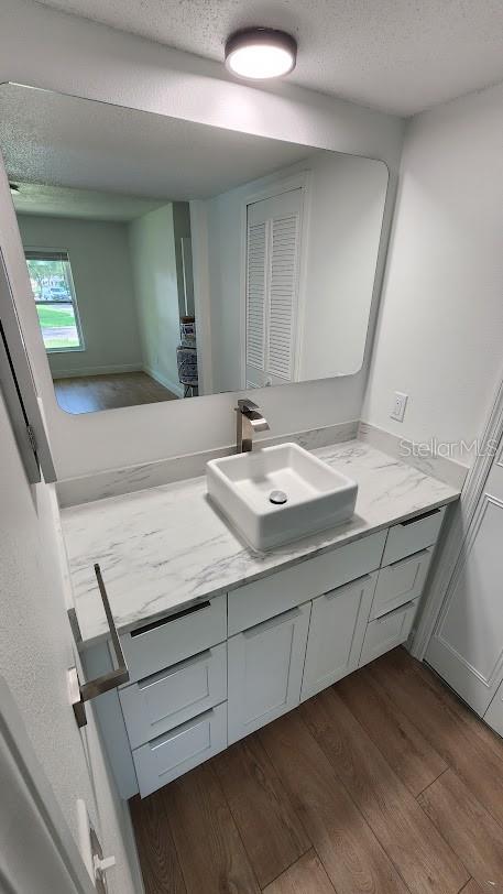 bathroom featuring hardwood / wood-style floors, vanity, and a textured ceiling