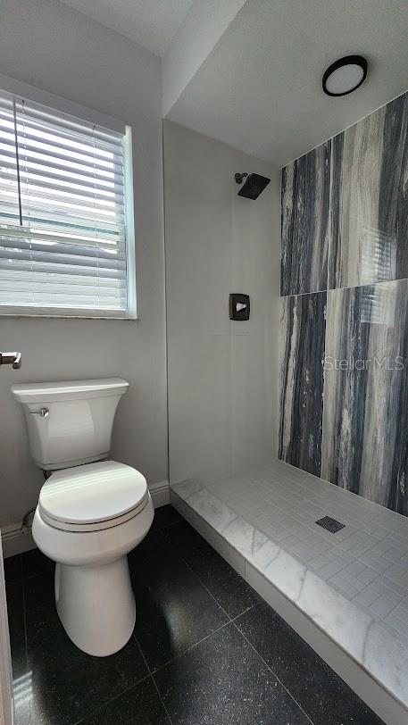 bathroom with a tile shower and toilet