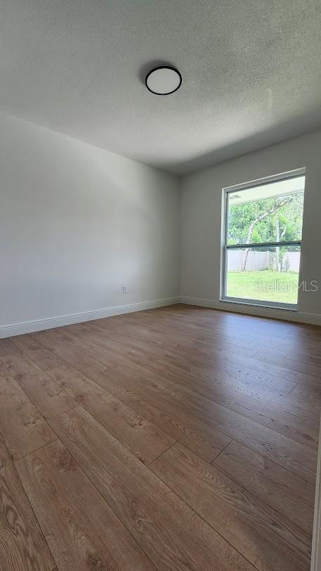 spare room featuring a textured ceiling and hardwood / wood-style flooring