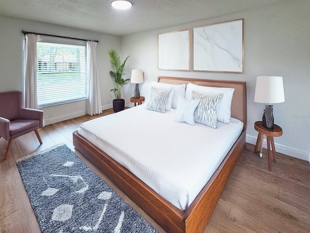 bedroom with a textured ceiling and hardwood / wood-style flooring