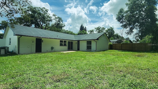 back of property featuring central AC and a yard