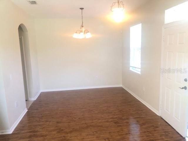 unfurnished room featuring dark hardwood / wood-style floors and a notable chandelier