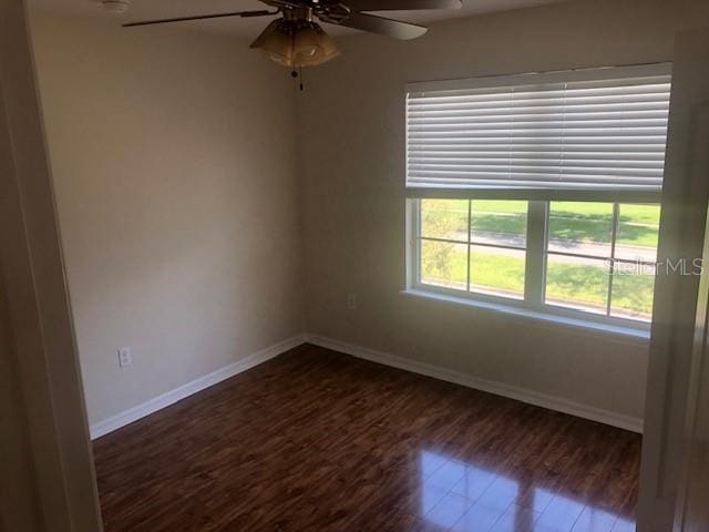 spare room with dark hardwood / wood-style floors and ceiling fan