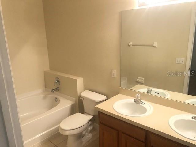 bathroom featuring tile patterned flooring, vanity, a washtub, and toilet