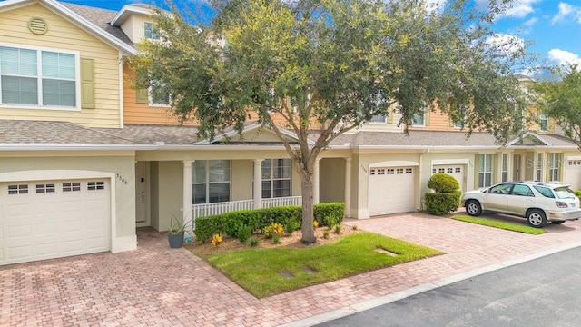 view of property featuring driveway, a shingled roof, an attached garage, and stucco siding