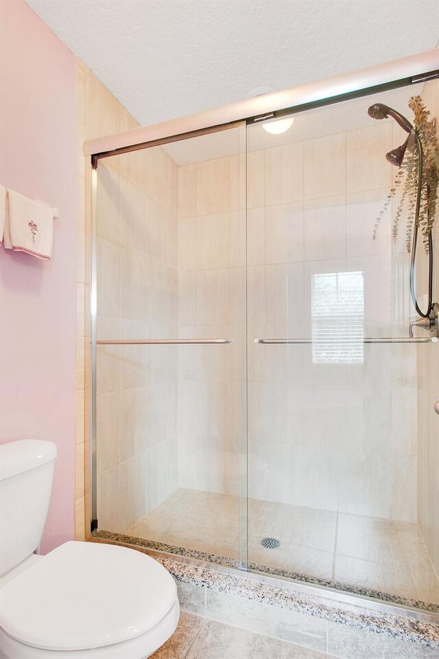 bathroom with toilet, tile patterned floors, and walk in shower